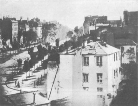 Photograph of man getting his boots polished (far left bottom corner) on Boulevard du Temple. Exposure time was so long that all traffic and pedestrians are not visible. This is acknowledged as the world’s first photograph. Photo by Louis Daguerre (c. 1838). Scanned and processed by Mariluna. PD-Author’s life plus 100 years or fewer. Wikimedia Commons.