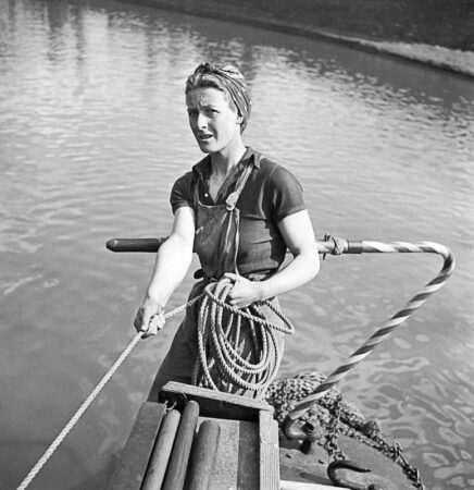 Daphne March at the tiller of her boat, “Heather Bell.” Photo by anonymous (c. 1942). Ministry of Information Second World War Official Collection. PD-Expired copyright. Wikimedia Commons.