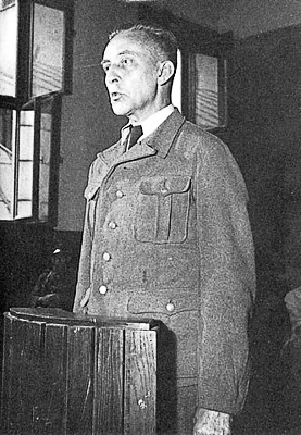 Jürgen Stroop testifying in the witness box during his trial. Photo by anonymous (c. July 1951). PD-Poland Public Domain. Wikimedia Commons.